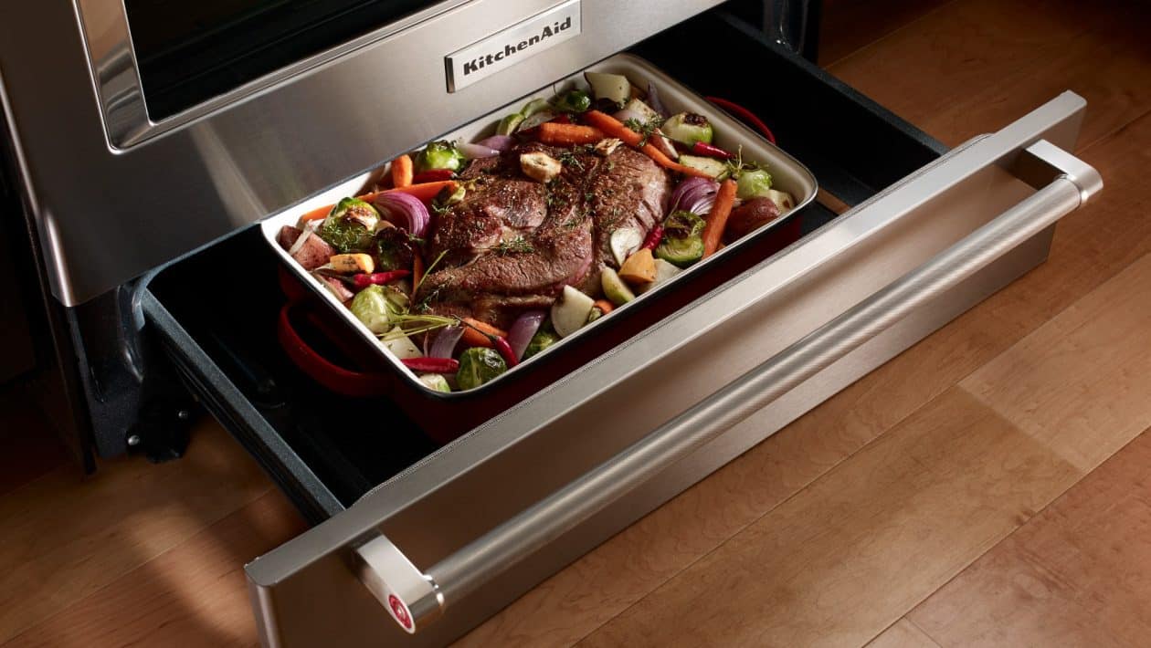 Geöffnete Schublade unter einem modernen Backofen mit vorgewärmten Tellern.